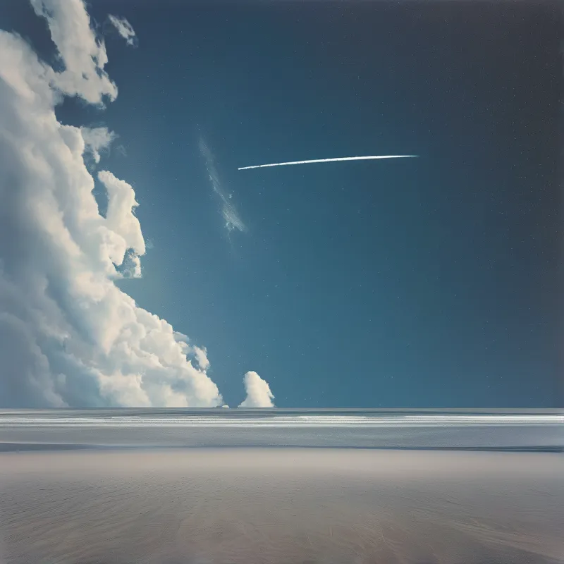 White contrails cross a deep blue sky above flat sandy terrain with large cumulus clouds on the left horizon.