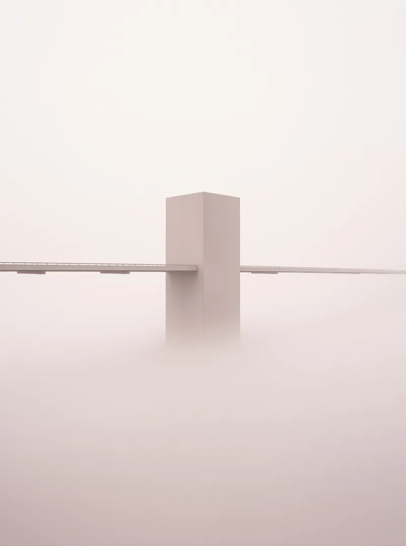 A large rectangular concrete pier supports a bridge deck while disappearing into thick white fog below.