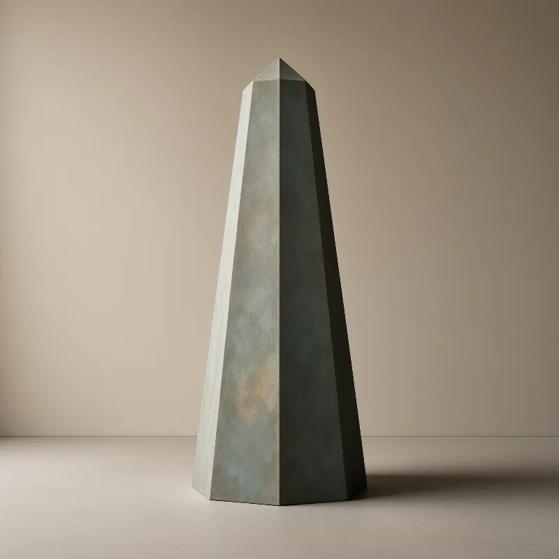A weathered faceted metal obelisk with blue green patina stands in a beige room lit from the left casting a shadow.