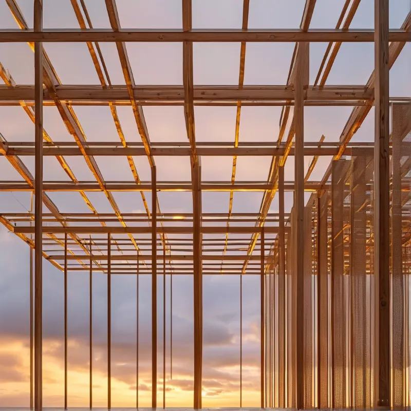 An exposed wooden building skeleton rises against a gradient sky transitioning from deep blue to warm orange near the horizon.