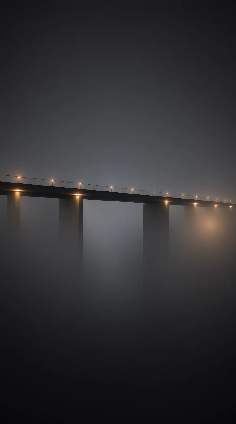 A long concrete bridge stretches horizontally across a foggy expanse illuminated by a row of warm amber streetlights.
