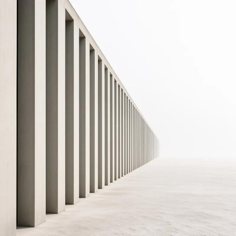 A row of tall vertical concrete slabs vanishes into a bright white void on a smooth pale floor.