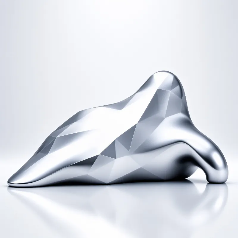 A polished silver object with faceted surfaces sits on a glossy white floor, reflecting the bright studio lighting.