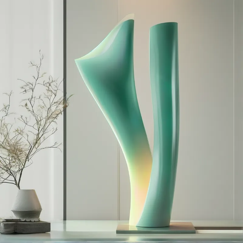 Two curved teal sculptures stand illuminated on a glass shelf beside a vase of dry branches.