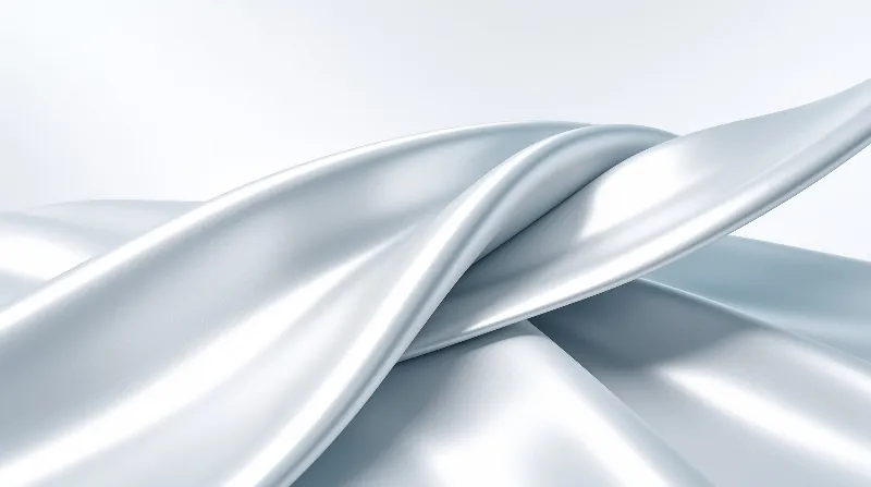 Glossy pale blue fabric ripples flow gently across a clean white surface with soft illumination.
