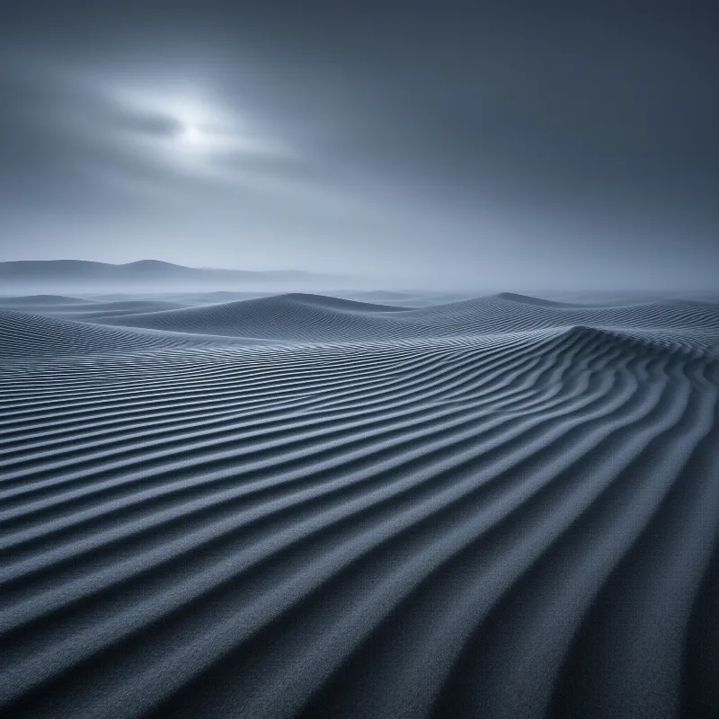 Vast desert sand dunes with rippling wind patterns stretching toward distant hills under a cloudy blue sky.