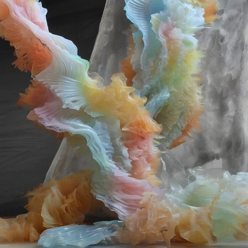 Translucent pastel layers of material drape downwards against a dark gray background revealing intricate striations.