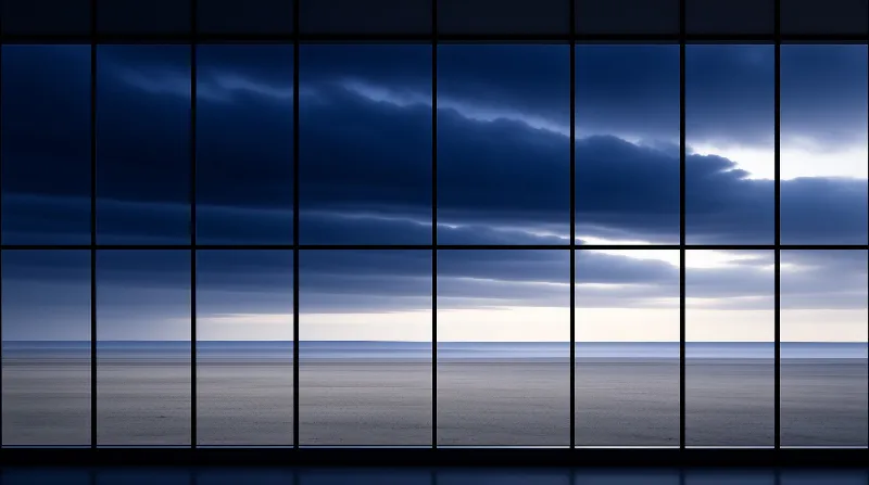 Dark clouds and a bright horizon are visible through a large grid of window panes during twilight.