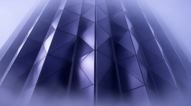 Looking up at a blue skyscraper with a geometric facade made of segmented glass panels.