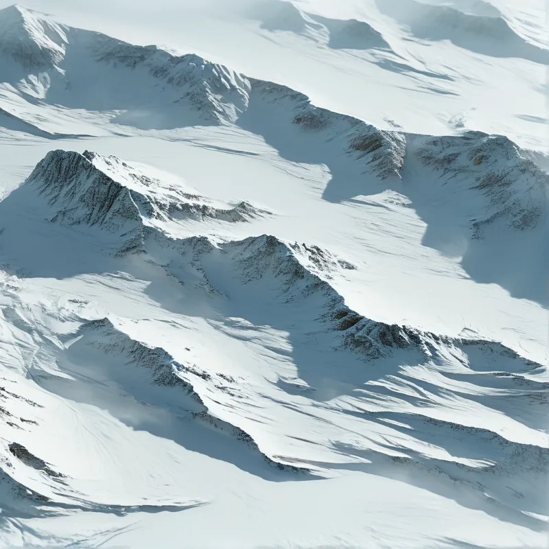 Aerial perspective of jagged snow-covered peaks casting long shadows across the white alpine terrain.