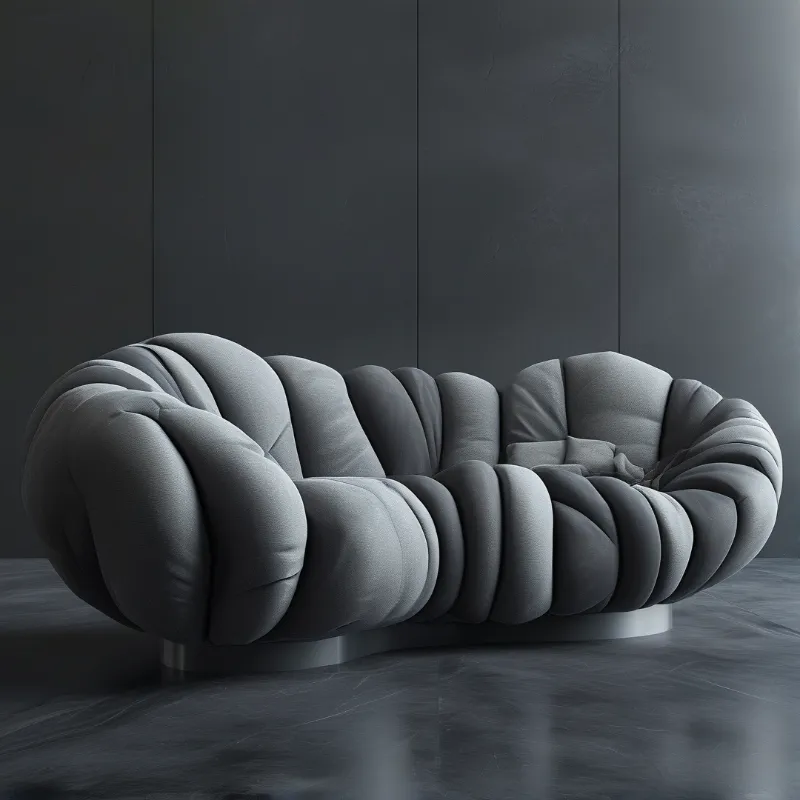A plump grey upholstered sofa with soft quilted curves sits on a dark reflective floor against charcoal walls