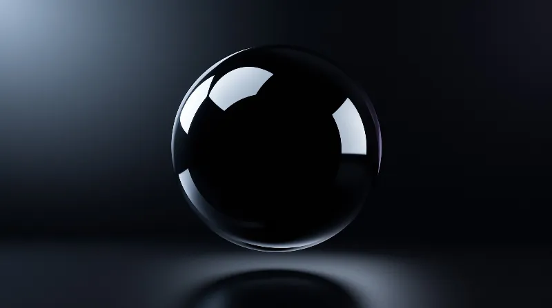 A glossy black orb floats above a reflective surface under focused white lighting.