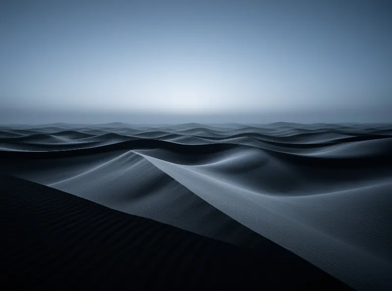 Dark blue monochromatic sand dunes with ripples stretch to a glowing horizon under a soft sky