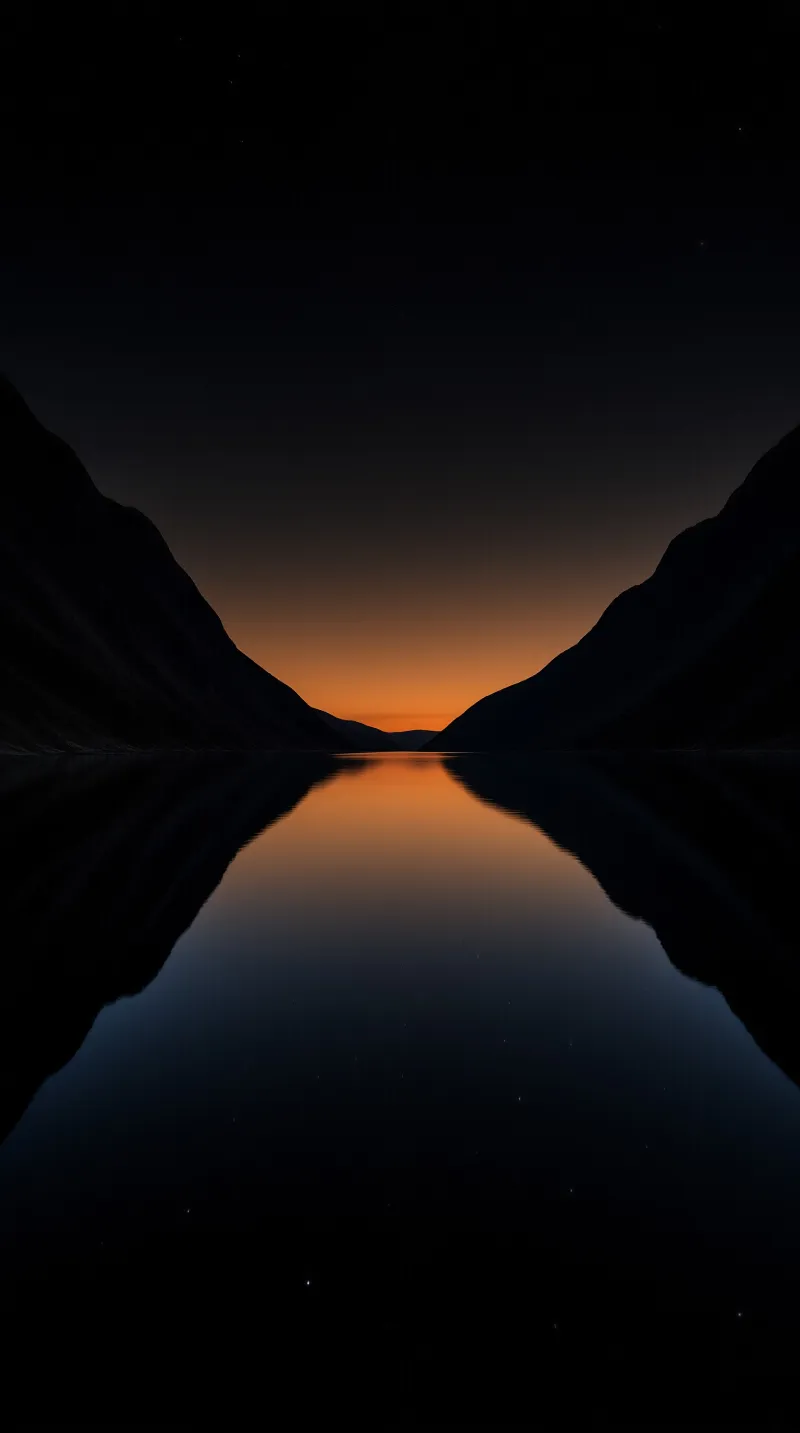 Dark mountain silhouettes frame a valley where an orange sky reflects perfectly in the still water below.