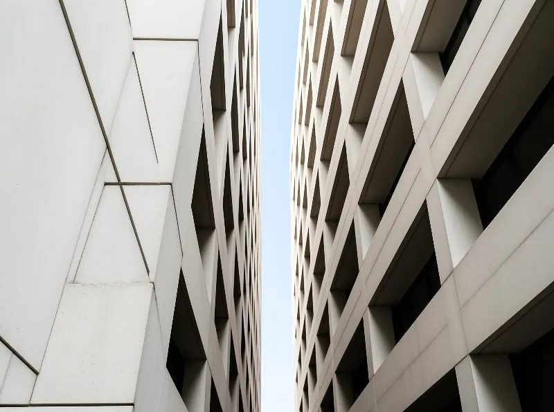A low angle view squeezes the blue sky into a thin wedge between angular panels and a dark window grid.
