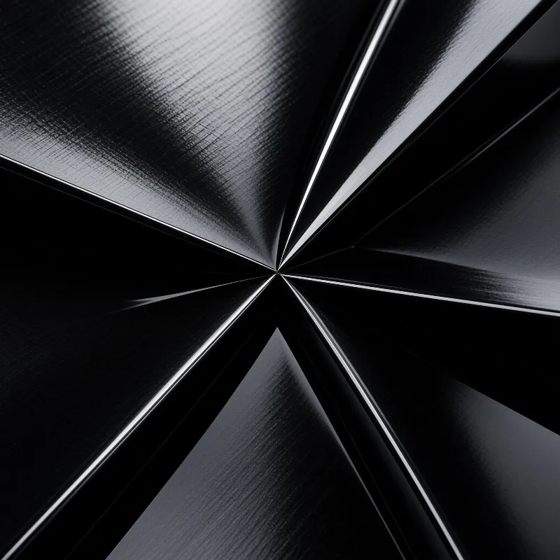 Shiny black material forms sharp ridges spreading from a center point under bright illumination.