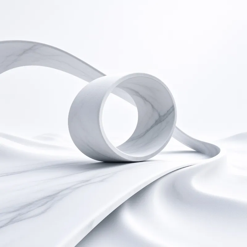A white marble veined cylindrical ring rests on rippled wavy white ground under soft diffused bright lighting.