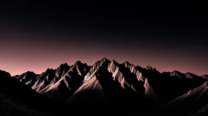 Jagged mountain peaks stand in silhouette against a gradient sky shifting from dark blue to pink near the horizon.