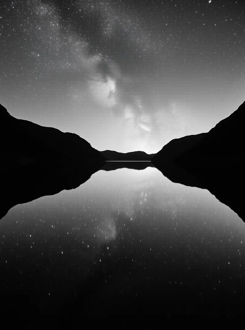 Dark mountain silhouettes frame a starry sky that mirrors perfectly in the lake below.