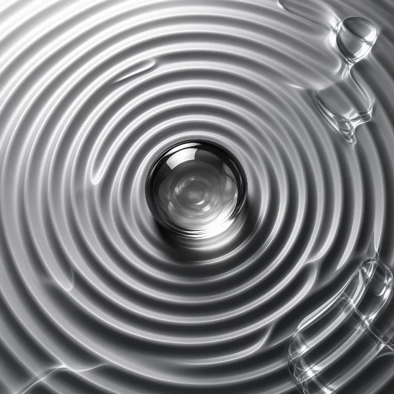Monochrome macro shot of concentric ripples radiating from a central reflective droplet surrounded by distorted liquid forms.