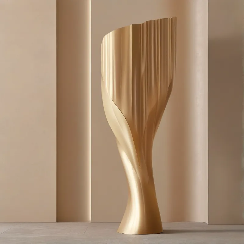 A twisting golden sculpture rests between smooth pale beige walls, bathed in gentle light highlighting its folded contours.