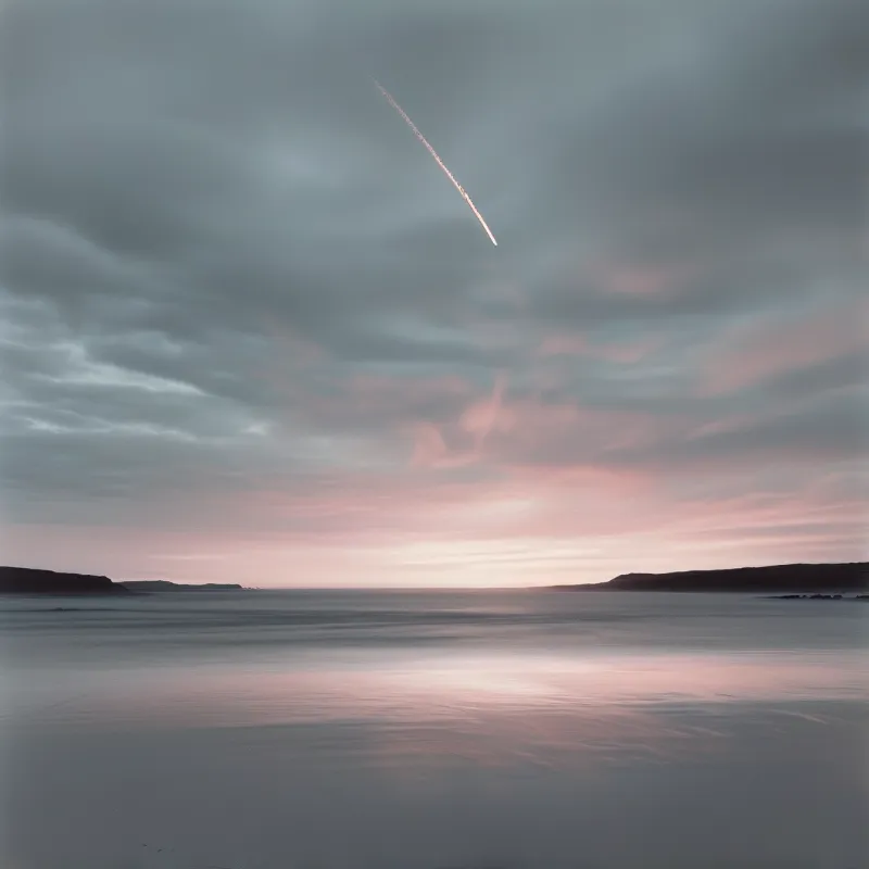 A smooth coastal water surface mirrors a pink and grey sky while a contrail streaks above dark land horizons.