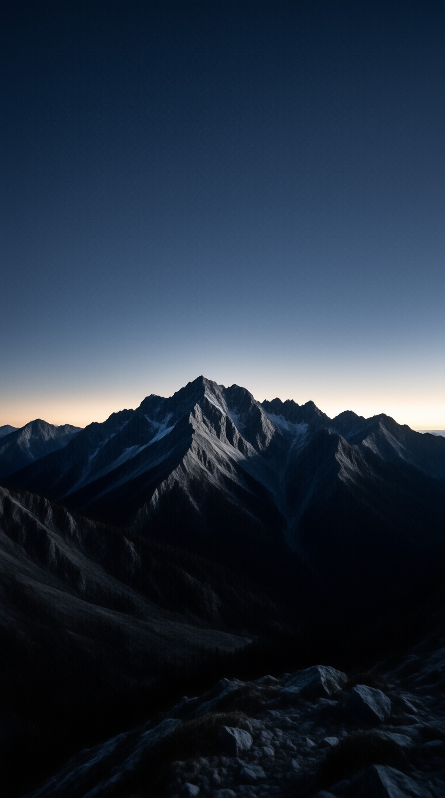 Dark rocky mountain ridges rise sharply against a gradient sky transitioning from deep blue to a faint warm horizon glow