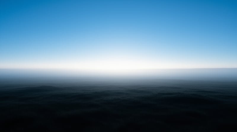 A dark expanse of water stretches beneath a bright gradient sky near the horizon.