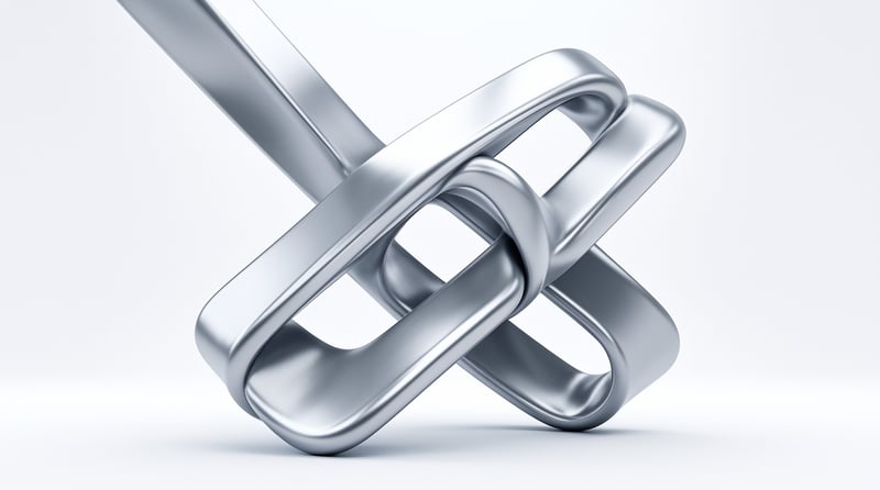 A close-up view of a shiny silver metal chain link resting on a plain white surface with soft reflections and smooth curves.
