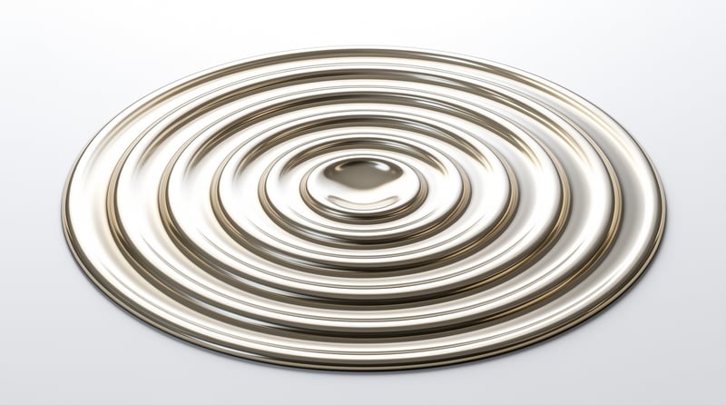 A gold metallic disc with spiral grooves rests on a white surface under bright studio lighting.